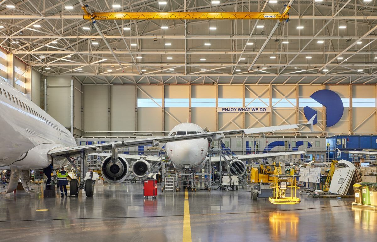 Aircraft inside FL Technics maintenance hangar, with engineers and equipment working on multiple planes.